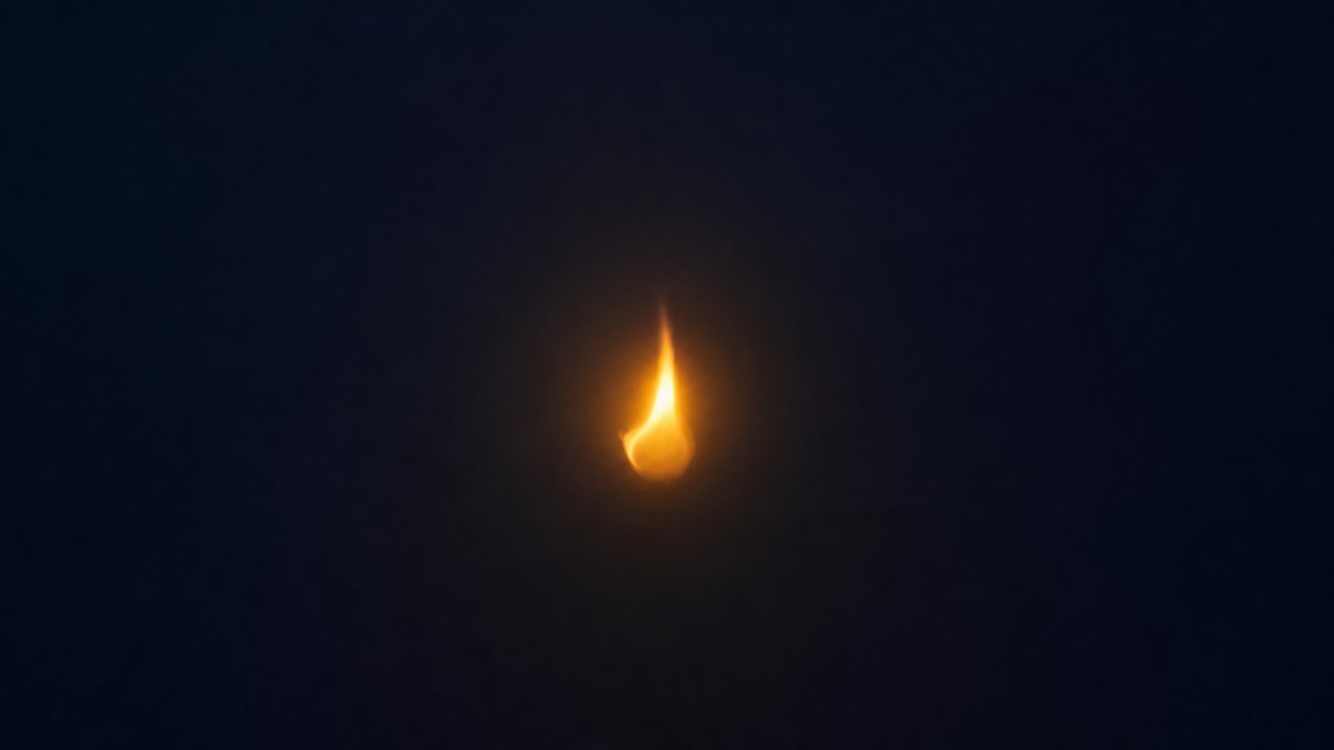 Petite flamme dorée dans l'obscurité — métaphore du début